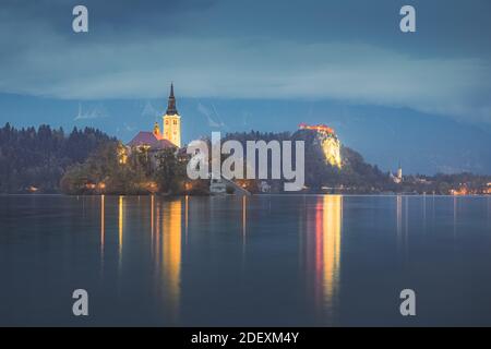 Splendido lago Bled al crepuscolo con la Chiesa del pellegrinaggio Dell'Assunzione di Maria e Castello di Bled illuminato Foto Stock