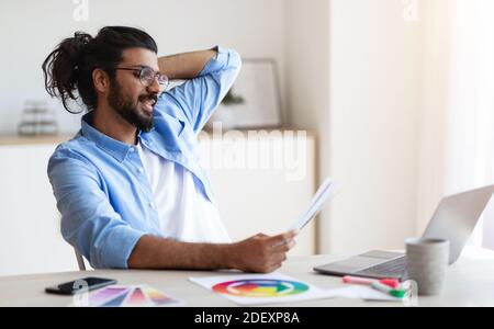 Designer occidentale che lavora con campioni di colore alla scrivania ufficio domestico Foto Stock