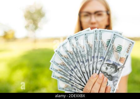 Bella ragazza con gli occhiali che tengono i soldi nelle sue mani, primo piano immagine di dollari Foto Stock