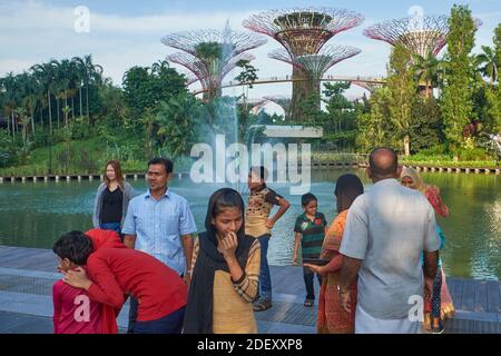 Turisti asiatici in Gardens by the Bay, Marina Bay, Singapore, con alcuni dei SuperTrees iconici sullo sfondo Foto Stock
