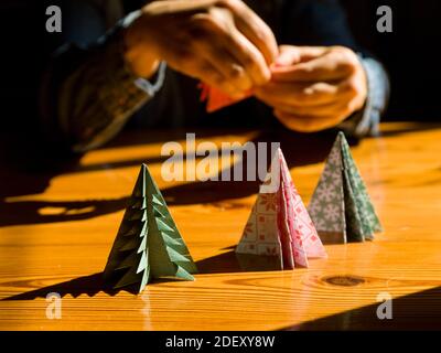 Creazione di regali di Natale decorazioni con alberi di Natale. Realizzata con le tue mani. Vista dall'alto del tavolo in legno con le mani femminili. Artigianato tempo libero per WO Foto Stock