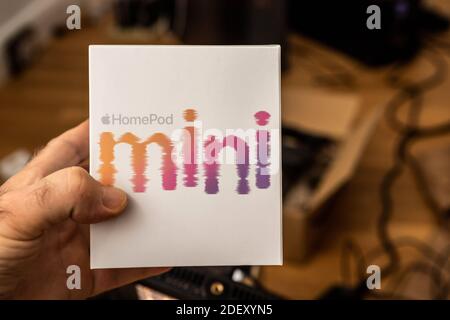 Francoforte, Germania - 17 novembre 2020: POV di mano maschile disimballaggio ultimi computer Apple HomePod Mini nuovo piccolo altoparlante intelligente con suono potente e assistente personale Siri Foto Stock