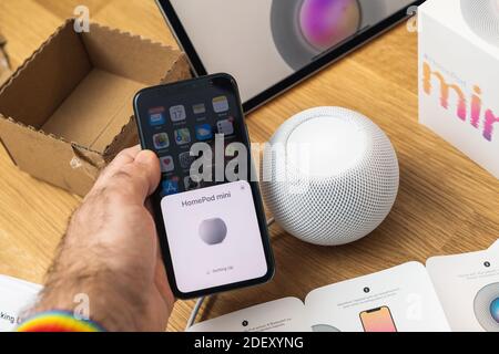 Francoforte, Germania - 17 novembre 2020: POV di mano maschile disimballaggio ultimi computer Apple HomePod Mini nuovo piccolo altoparlante intelligente con suono potente e assistente personale Siri - configurazione Foto Stock
