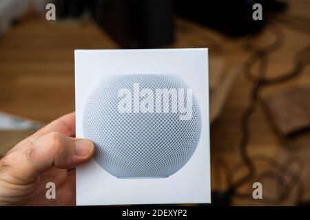 Francoforte, Germania - 17 novembre 2020: POV di mano maschile disimballaggio ultimi computer Apple HomePod Mini nuovo piccolo altoparlante intelligente con suono potente e assistente personale Siri Foto Stock