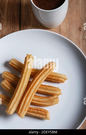 Churros con cioccolato su fondo di legno. Immagine isolata e verticale Foto Stock