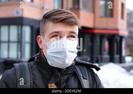 Giovane uomo nella maschera dell'influenza sulla City Street Primo piano verticale Foto Stock