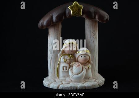 Rappresentazione di un presepe natalizio con le piccole figure di Gesù bambino, Maria e Giuseppe su sfondo nero. Concetto di Natale. Foto Stock