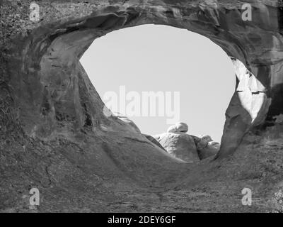 Una foto in bianco e nero di Tunnel Arch, uno degli archi più piccoli nella sezione Giardino del Diavolo del Parco Nazionale Arches, Utah. Foto Stock