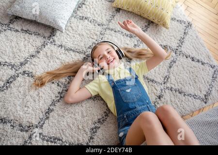 Ragazza adolescente sdraiata sul tappeto da terra, ascoltando musica Foto Stock