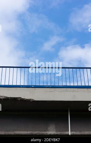 Un'immagine verticale ad angolo basso di una ringhiera metallica a ponte con un cielo nuvoloso dietro Foto Stock