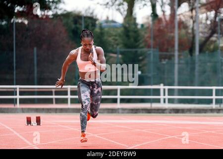 Foto d'inventario di uno sprinter afroamericano che corre su una atletica traccia Foto Stock