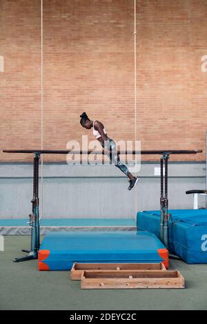 Foto di borsa di una ginnastica afroamericana che pratica in parallelo barre Foto Stock