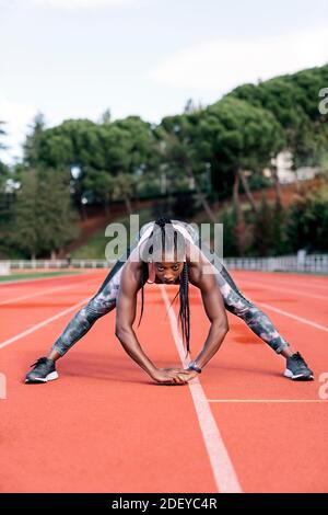 Foto d'inventario di una velocista afroamericana che tende le gambe prima formazione Foto Stock