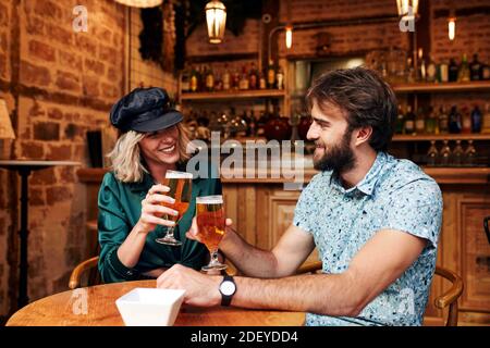 Foto di scorta di una coppia nei suoi 30 anni che beve un drink in un bar. Sorridono e ridono. Indossano un panno casual. Foto Stock