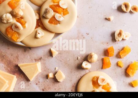 I mendianti di cioccolato biondo alle nocciole e alle albicocche su un piatto con ingredienti sul lato. Foto Stock