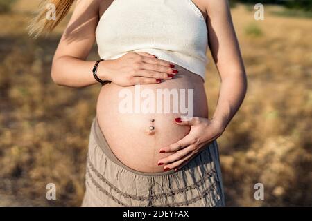 Foto di scorta di una donna incinta non riconosciuta che tocca il ventre. Foto Stock