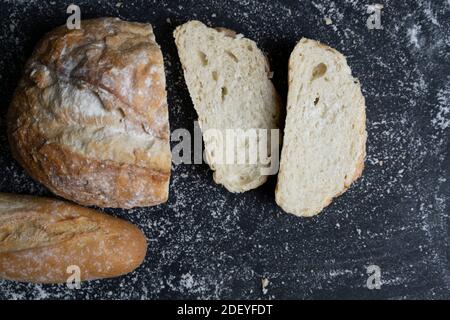 Varietà di pane tradizionale con fette di pane su fondo nero floury.concetto di ricetta, cottura e ingredienti sani di fondo. Foto Stock