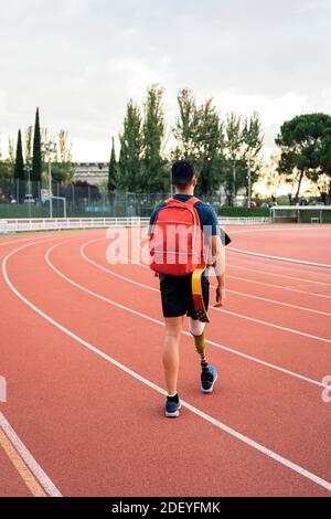 Foto di stock di atleta inriconosciuto che cammina con il suo zaino in pista. Foto Stock
