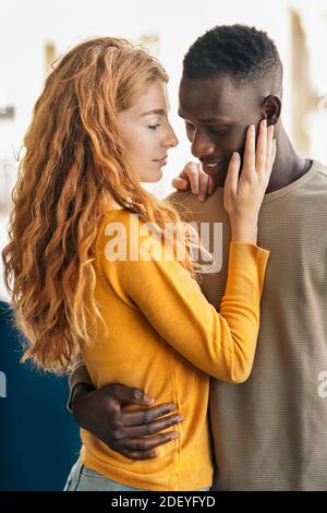 Foto d'inventario di una giovane coppia multietnica che si abbracca e si bacia. Foto Stock