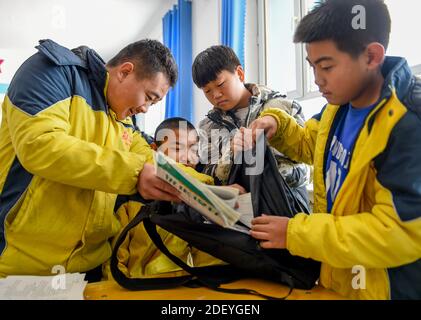 (201202) -- CHIFENG, 2 dicembre 2020 (Xinhua) -- Sun Simiao (1°, L) e i suoi compagni di classe aiutano Wang Aoran a portare la sua borsa scolastica nella scuola di Chifeng City, regione Autonoma della Mongolia interna della Cina del nord, 25 novembre 2020. Wang Aoran, 15 anni, è stato disabilitato in azione da anomalie della creatina chinasi da quando era un bambino. Al secondo grado di scuola elementare, ricevette l'aiuto del compagno di scuola Sun Simiao, che volontariamente iniziò a portarlo dalla porta della scuola alla sua classe. Da allora lo ha aiutato. I due divennero inseparabili migliori amici. Andarono alla stessa scuola media, entrambi Foto Stock