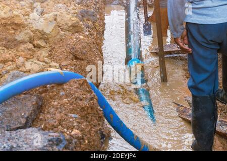 lavori idraulici, scavo, riparazione, tubazione dell'acqua, collegamento tubo principale in PVC impianto idraulico su strada e retroescavatore (movimento dell'acqua) Foto Stock