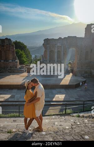 Uomini e donne di coppia visitano le rovine del teatro greco antico a Taormina sullo sfondo del vulcano Etna, Italia. Taormina si trova nella Città Metropolitana di Messina, sulla costa orientale dell'isola di Sicilia Italia Foto Stock