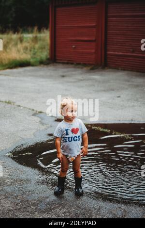 Adorabile giovane ragazzo che indossa stivali in gomma accanto a a. puddle Foto Stock