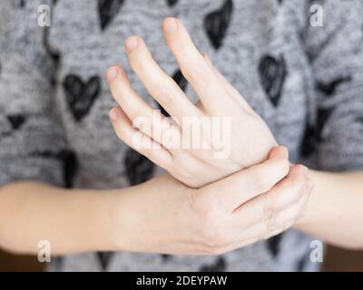 Primo piano giovane donna bianca che soffre di dolore al polso sinistro. Salute c Foto Stock