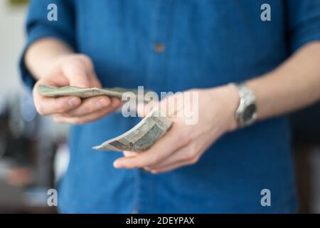 Un giovane ricco in un ambiente informale e maglietta blu tenendo un sacco di soldi polacco Foto Stock