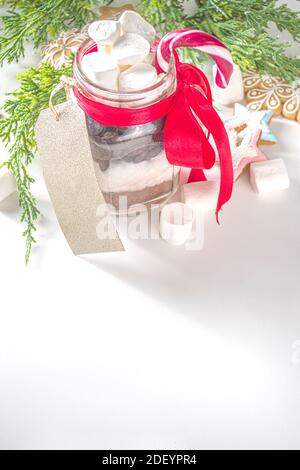 Miscela secca di cioccolato caldo in vasetto di muratore. Natale e inverno regali fatti a mano idea. Regalo di Natale commestibile fatto a mano, su sfondo bianco con Natale gi Foto Stock