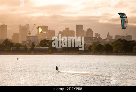 Una donna kiteboarding in un pomeriggio estivo con il Boston skyline Foto Stock