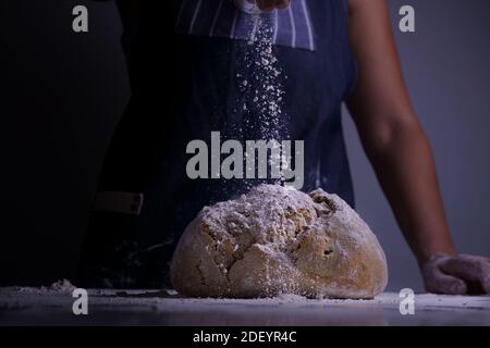 Donna che spalma la farina su un pane grande Foto Stock