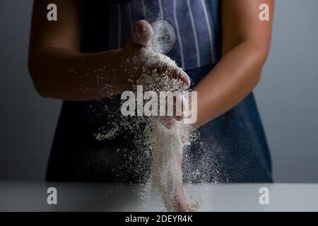 Donna che agita la farina nelle mani per fare il pane Foto Stock