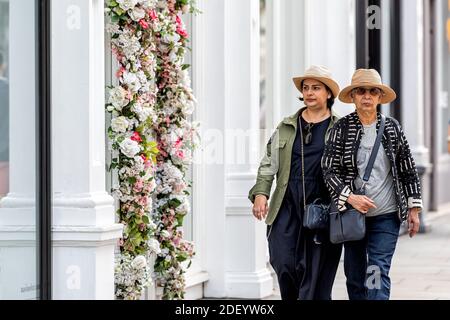 Londra, Regno Unito - 23 giugno 2018: Terrazza terrazzata bianco vittoriano appartamento edifici con fiori finti decorazioni e madre asiatica con figlia su Foto Stock