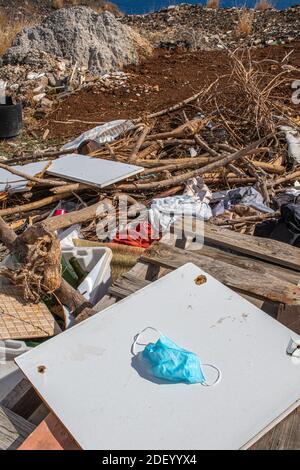 Maschera chirurgica gettata via nel mezzo della spazzatura. Verticale Foto Stock