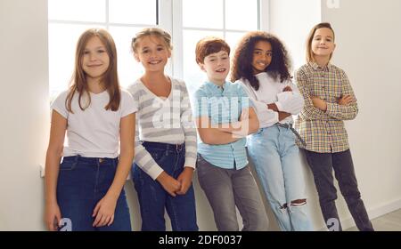 Sorridendo diversi bambini in piedi vicino alla finestra a casa o. durante la pausa a scuola Foto Stock