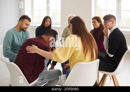 Persone diverse che sostengono e confortano i giovani gridando in gruppo sessione di terapia Foto Stock