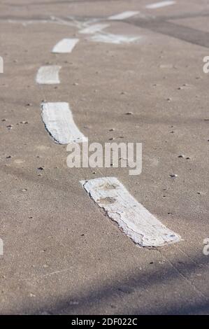 Linee bianche interrotte su una strada asfaltata che indicano che è possibile cambiare corsia. Foto Stock
