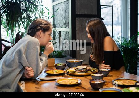Due ragazze del liceo che gossipano in un caffè asiatico. Foto Stock