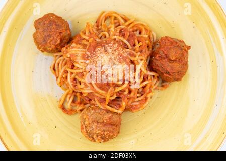 La vista dall'alto dell'autentico cibo italiano mostra un piatto per bambini di spaghetti e polpette ricoperte di salsa marinara e pronte da mangiare. Foto Stock