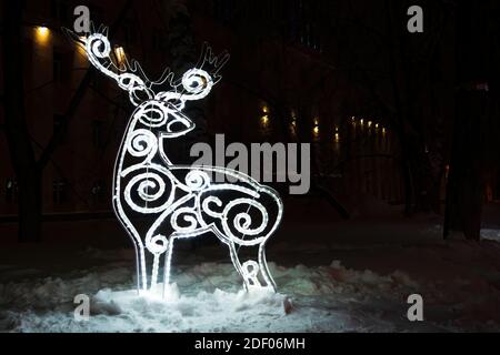 Figura di cervo da ghiaino in oscura notte d'inverno nella neve. Decorazioni natalizie. Spazio di copia Foto Stock