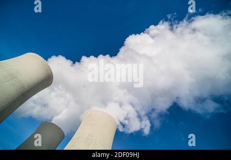 Cima delle torri di raffreddamento ad acqua della centrale nucleare e del pennacchio di vapore bianco sul cielo blu. Primo piano della produzione di nebbia nella moderna stazione di generazione. Ambiente. Foto Stock