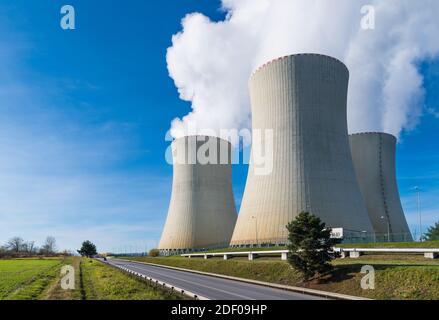 Torri di raffreddamento della centrale nucleare con bagne di vapore acqueo su sfondo blu. Moderna stazione di generazione in paesaggio, strada e tubazioni a vapore. Eco. Foto Stock