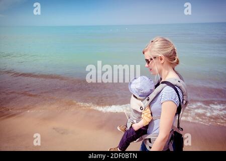 Madre che porta il bambino figlio lungo la spiaggia dell'Indiana Dunes National Park Foto Stock