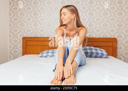 Al mattino una giovane bella ragazza in camera da letto che si svegliò e raggiunse dopo una buona notte di sonno Foto Stock