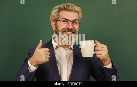 Dipendenza dal caffè. Carica di energia per tutto il giorno. Piacevole sorso. Pausa caffè e relax. Pranzo per insegnante. Dose di caffeina. Concetto di ottimismo. Insegnante in bicchieri bere caffè chalkboard sfondo. Foto Stock