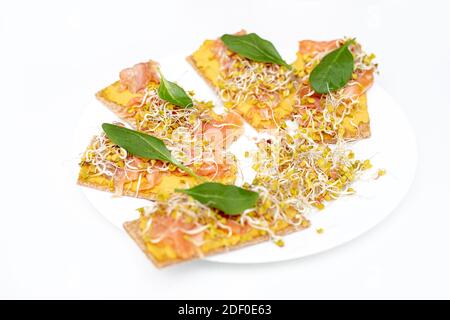 Bruschetta italiana vegetariana con salmone di pesce, verdure, foglie di spinaci e cereali germogliati, fuoco selettivo. Primo piano Foto Stock