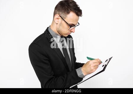 uomo d'affari in un vestito, tenendo un foglio bianco di carta, scrivendo un programma di affari, su uno sfondo bianco Foto Stock