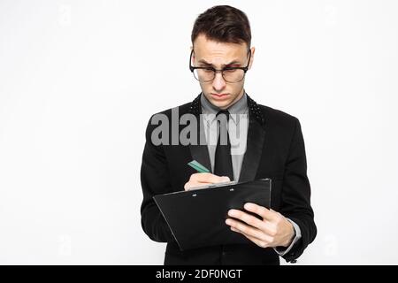 uomo d'affari in un vestito, tenendo un foglio bianco di carta, scrivendo un programma di affari, su uno sfondo bianco Foto Stock