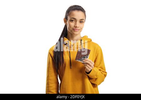 Giovane femmina in una felpa gialla che mangia un cioccolato isolato su sfondo bianco Foto Stock